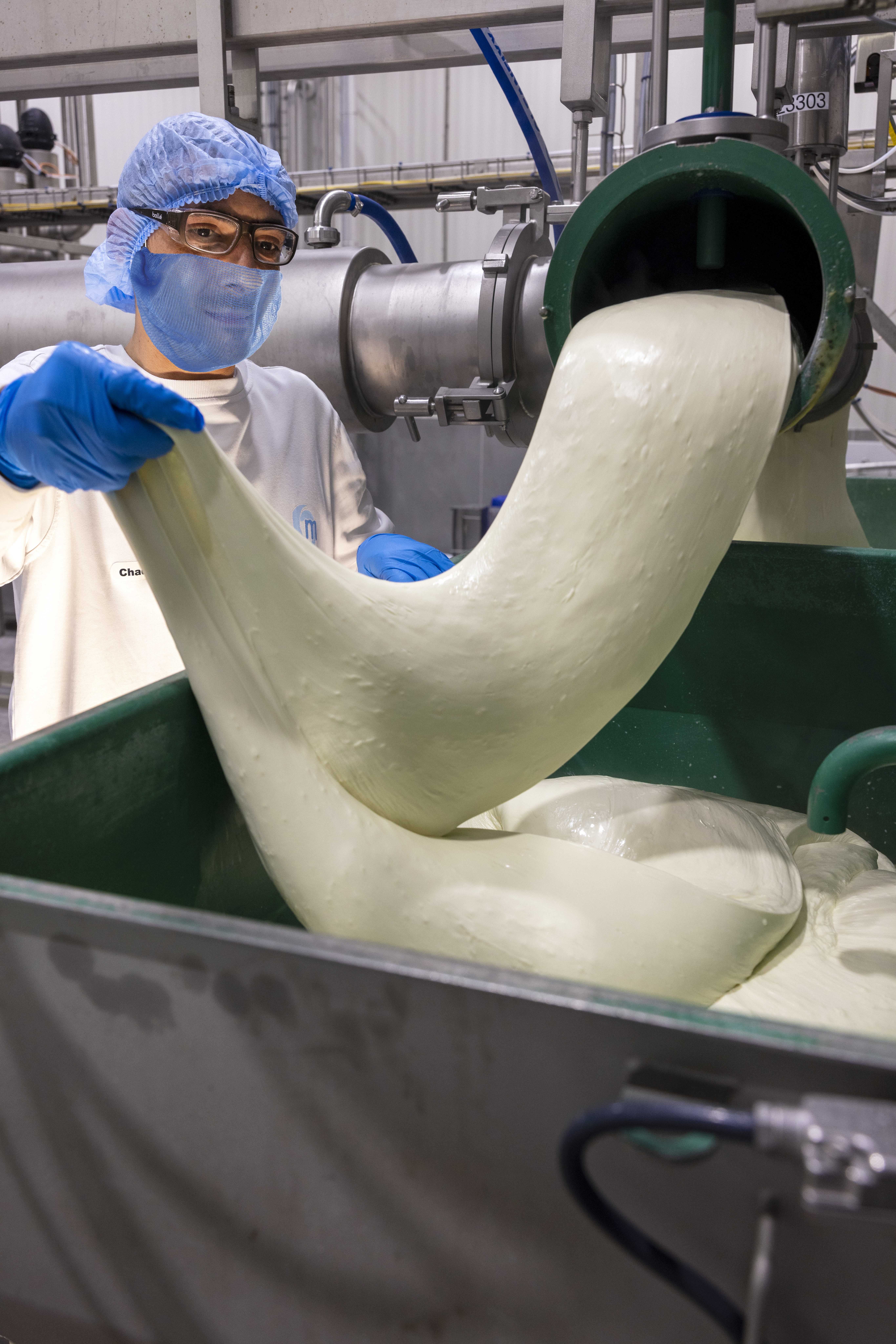 A person holding up the mouldable Cheese in the factory