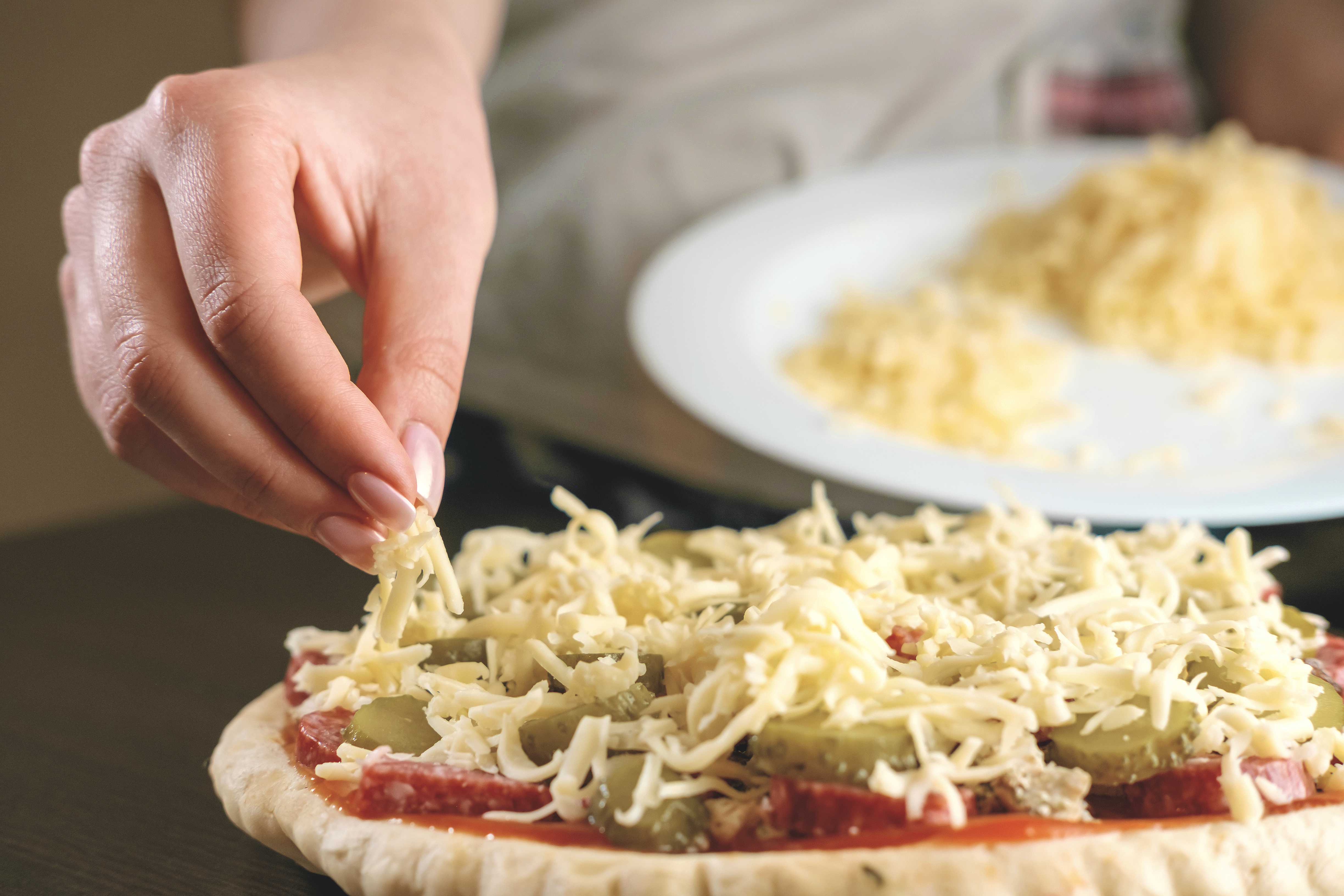 Shredded cheese being added as a pizza topping