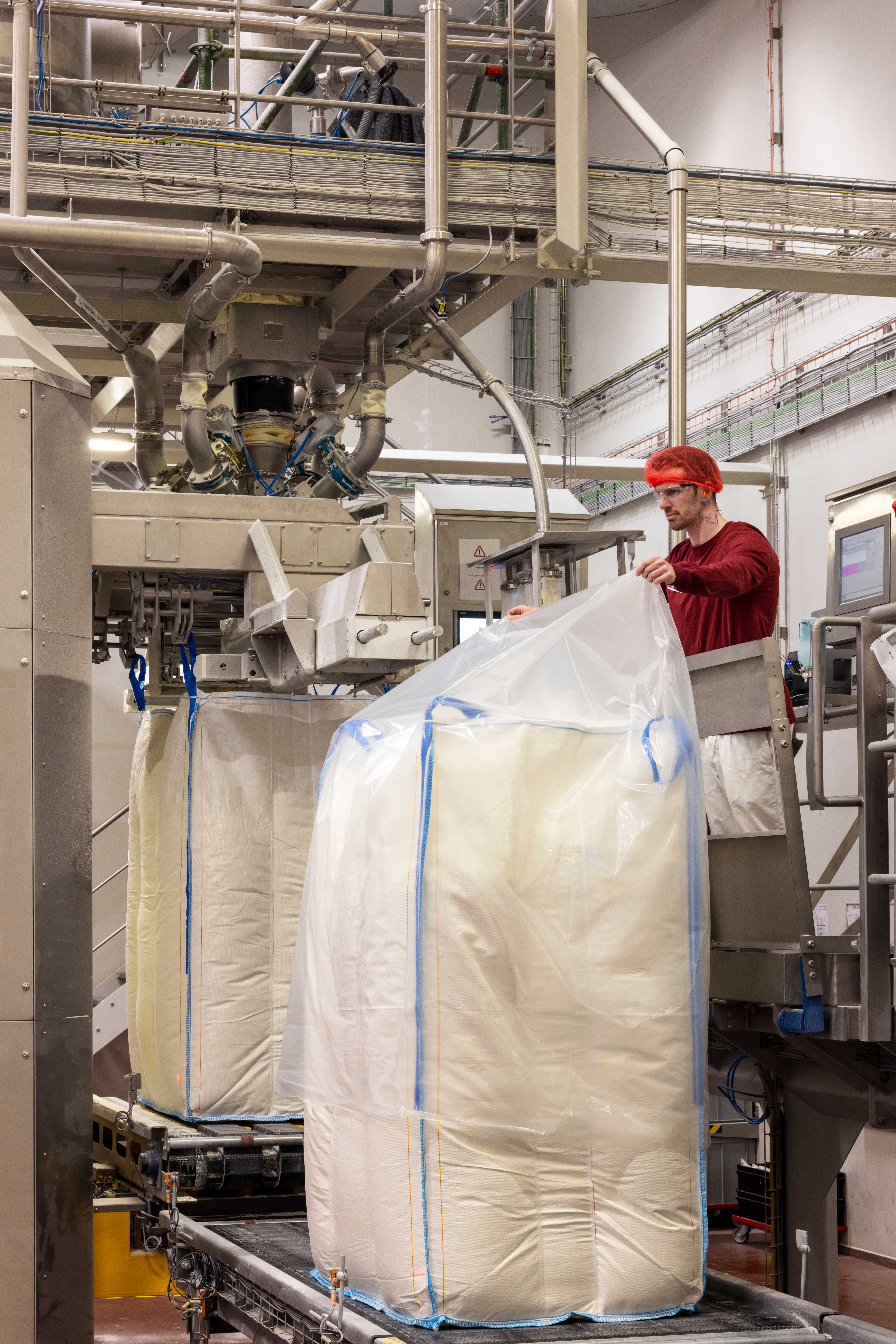 A man holding a big plastic bag over a block of mozzarella
